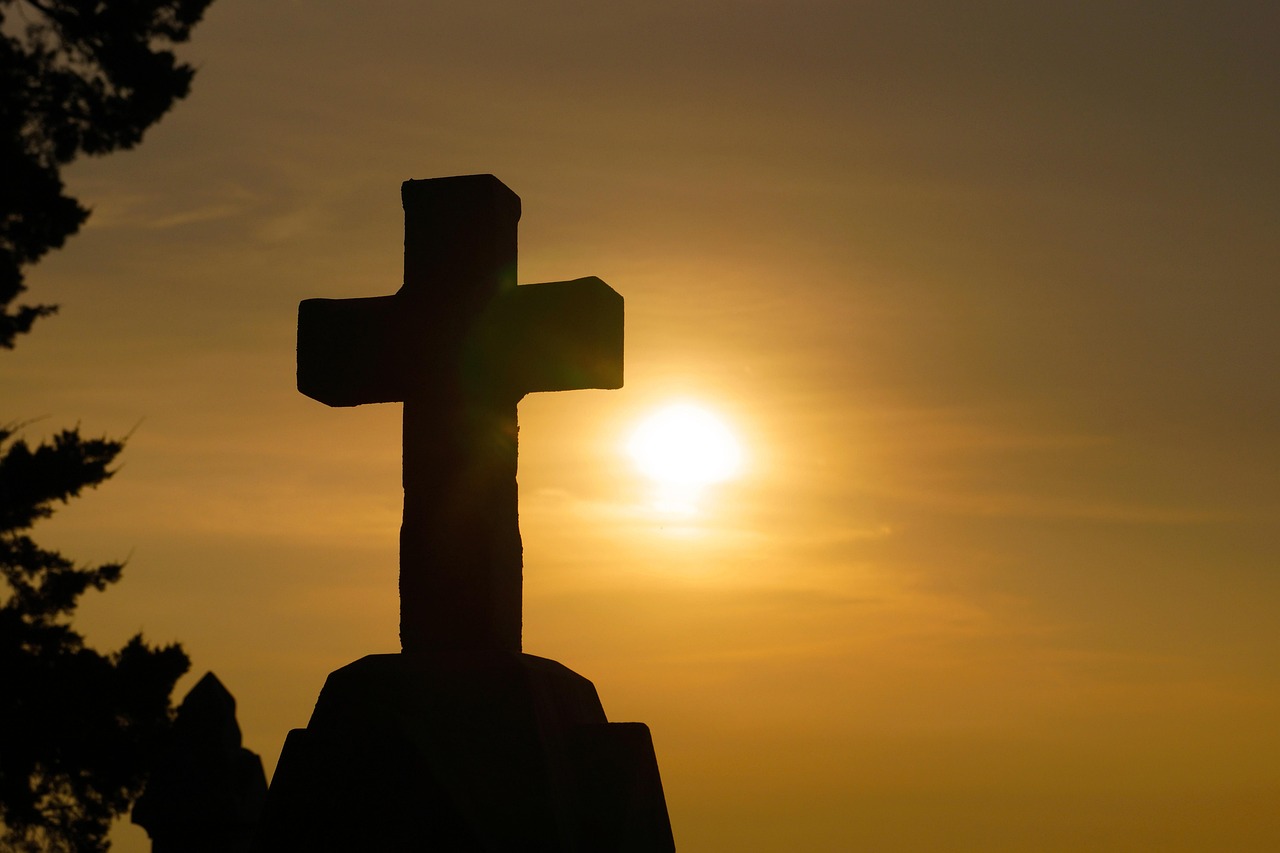 Cruz com luz ao entardecer, símbolo do perdão e da misericórdia de Deus