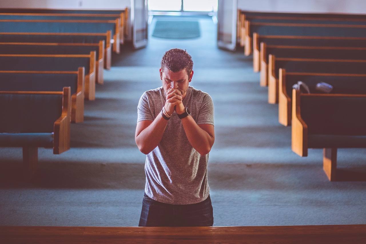 Homem ajoelhado em oração na igreja, momento de contrição e arrependimento