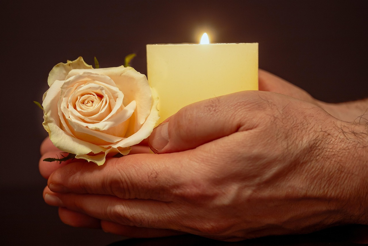 Mãos em oração com vela e rosa, símbolo de esperança nas causas impossíveis