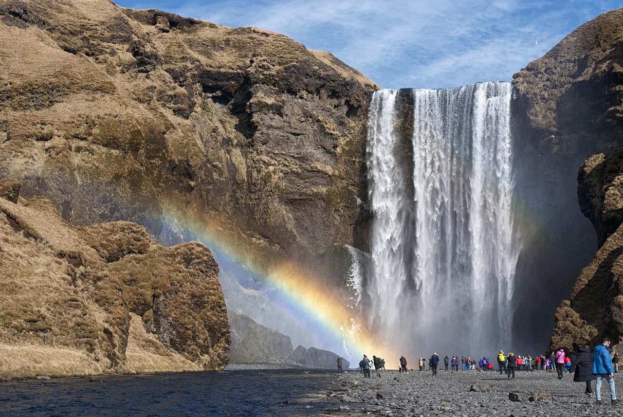 Cachoeira e arco-íris em paisagem montanhosa, símbolo de restauração após a queda