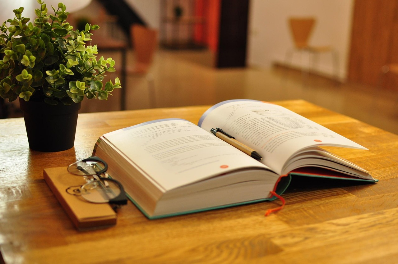 Livros abertos sobre mesa de estudo, representando a dedicação aos estudos