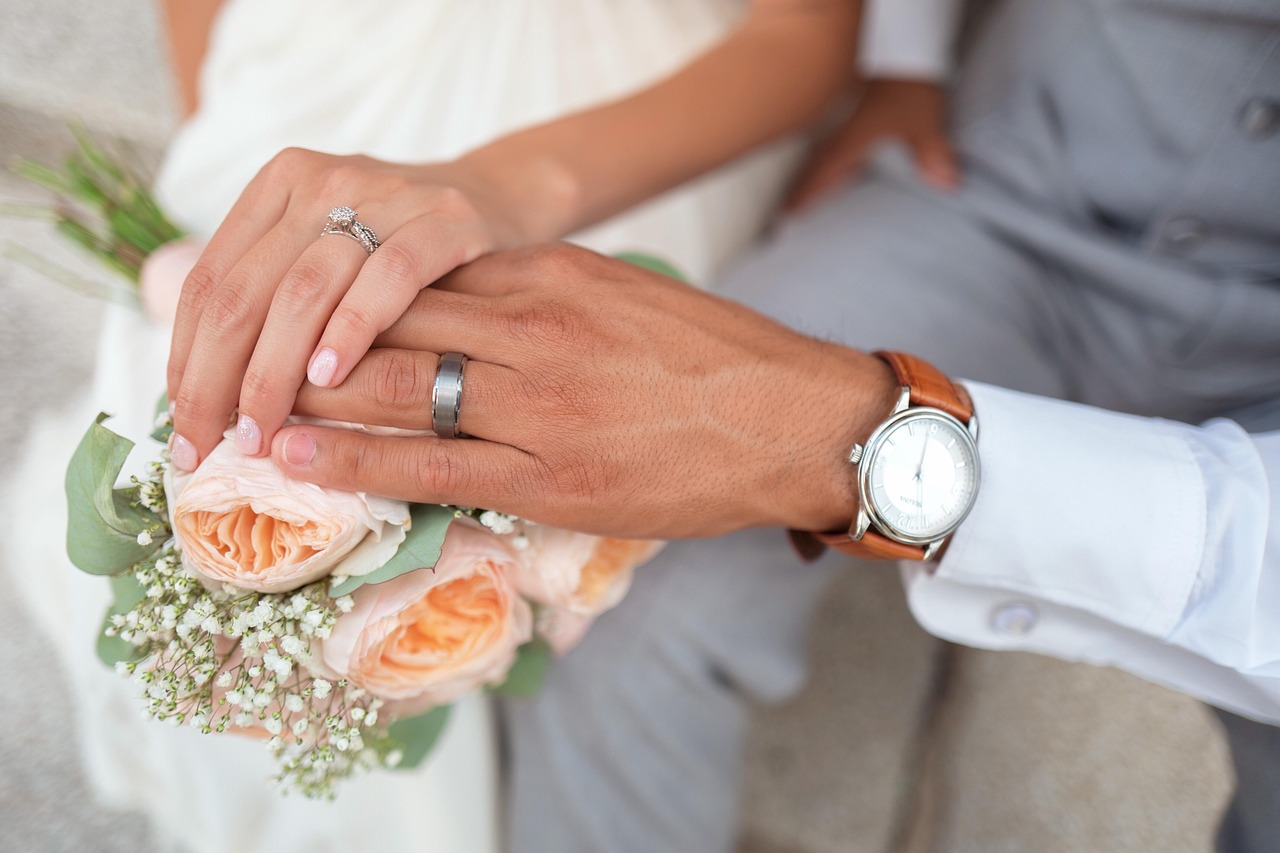 Noivos de mãos dadas com alianças de casamento