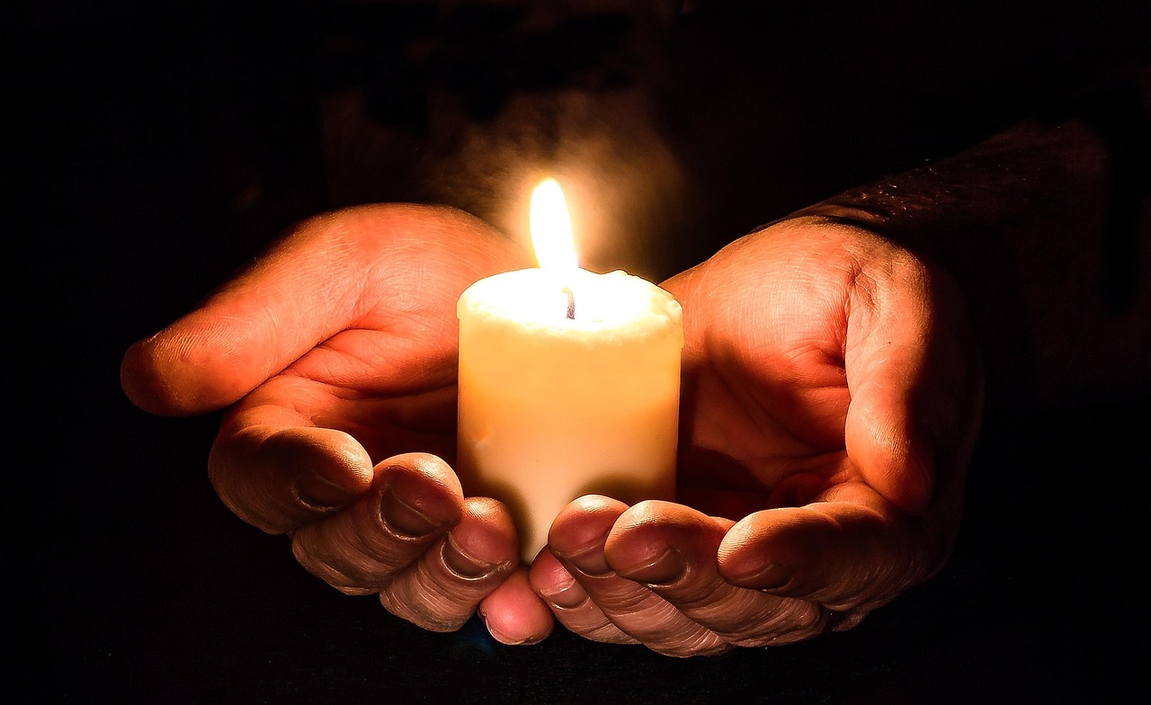 Mãos abertas à luz de velas, símbolo de confiança e esperança