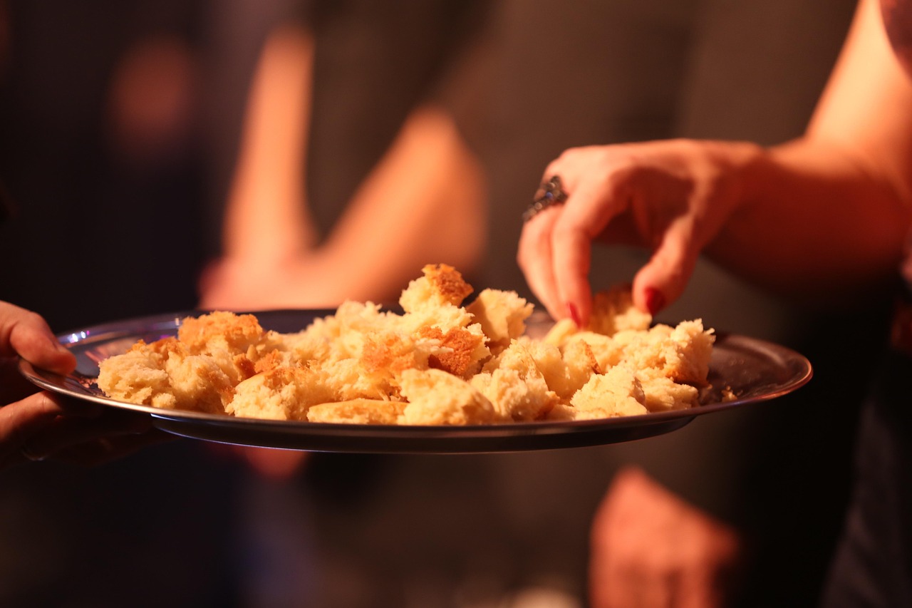 Mãos servindo pão, símbolo do serviço de caridade dos ministros leigos