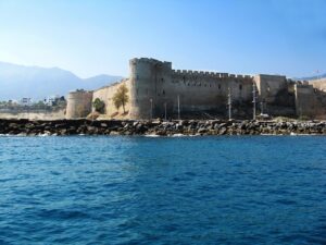 Castelo litorâneo no Mediterrâneo, referência ao porto de Óstia onde Santa Mônica morreu